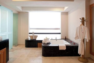 A modern bathroom with a large bathtub, a vanity with a sink, and a robe stand.