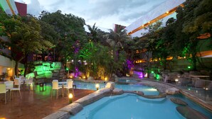 Una piscina interior de varios niveles con zonas de estar y abundante vegetación.