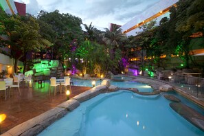 Relax by the pool surrounded by lush greenery and rock formations.