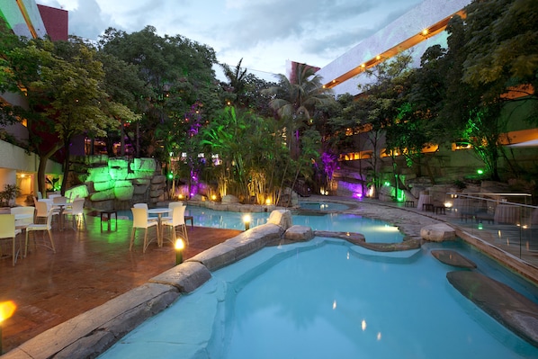 A multi-level indoor pool with seating areas and lush greenery.