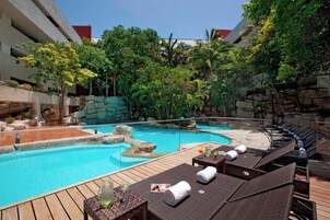 Un área de piscina con sillones de descanso y una terraza de madera.