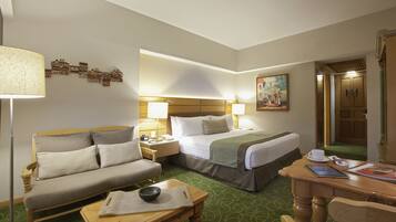 A hotel room with a bed, a sofa, a table, and a lamp.