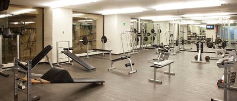 Uma academia com diversos equipamentos de exercício, incluindo esteiras, aparelhos de musculação e pesos livres.