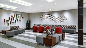 A modern lobby with a check-in counter, seating area, and a patterned wall design. - Wyndham Houston Sugarland (Houston)