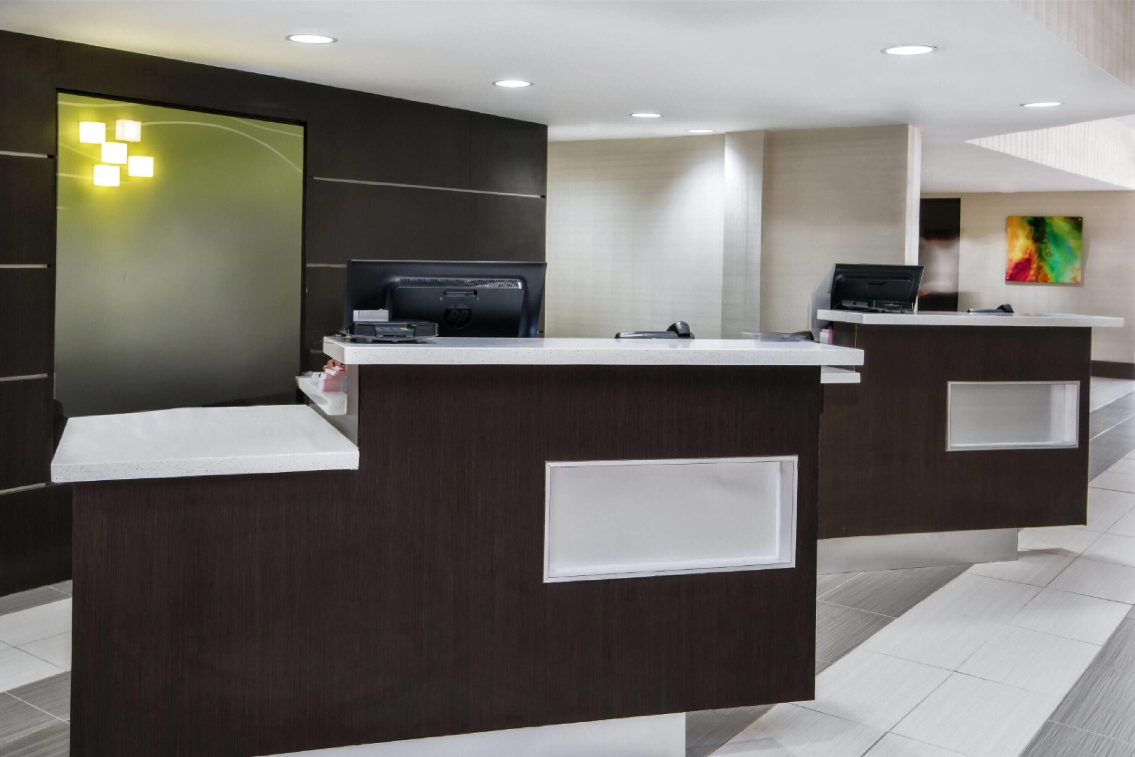 A modern reception desk with a flat-screen TV, a computer, and a phone.