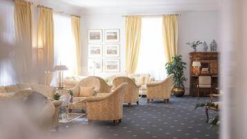 Een goed verlichte woonkamer met gestreepte banken, een bijzettafeltje en een open haard.
