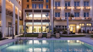 Un hôtel doté d’une piscine, de nombreux balcons et d’une façade bien éclairée.