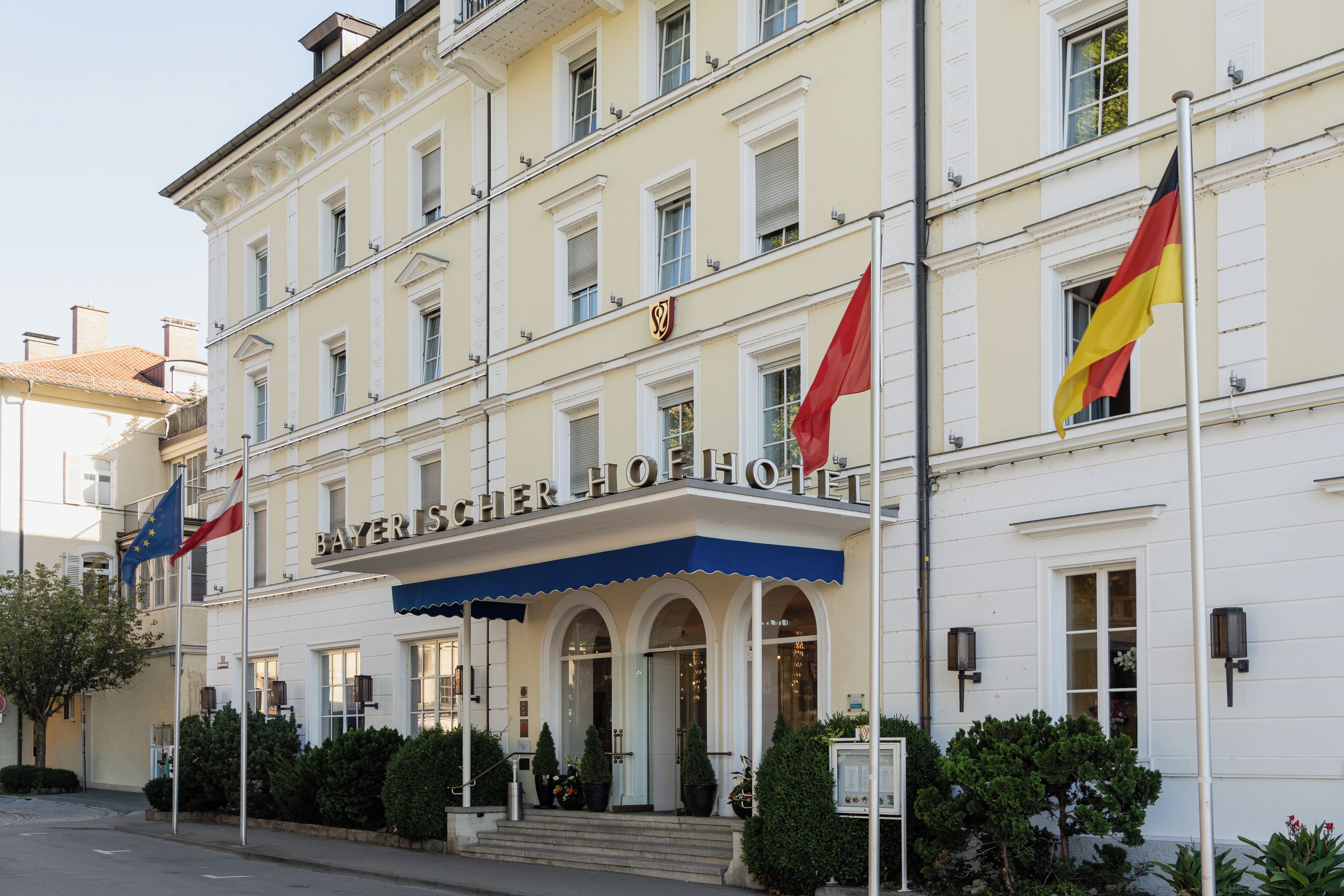 Ein Hotel mit einer klassischen Fassade, mehreren Flaggen und einem markanten Eingang mit Stufen zum Hauseingang.