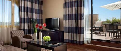 Una sala de estar moderna con cortinas a rayas, un televisor de pantalla plana, sofás a rayas y un comedor con asientos exteriores.