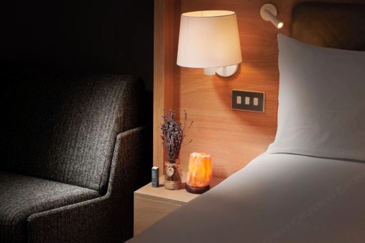 A hotel room with a bed, a nightstand, a lamp, and a decorative item.