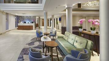 A spacious lobby with a reception desk, seating area, and decorative plants.