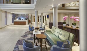 A spacious lobby with a reception desk, seating area, and decorative plants. - Hilton London Croydon (Croydon)