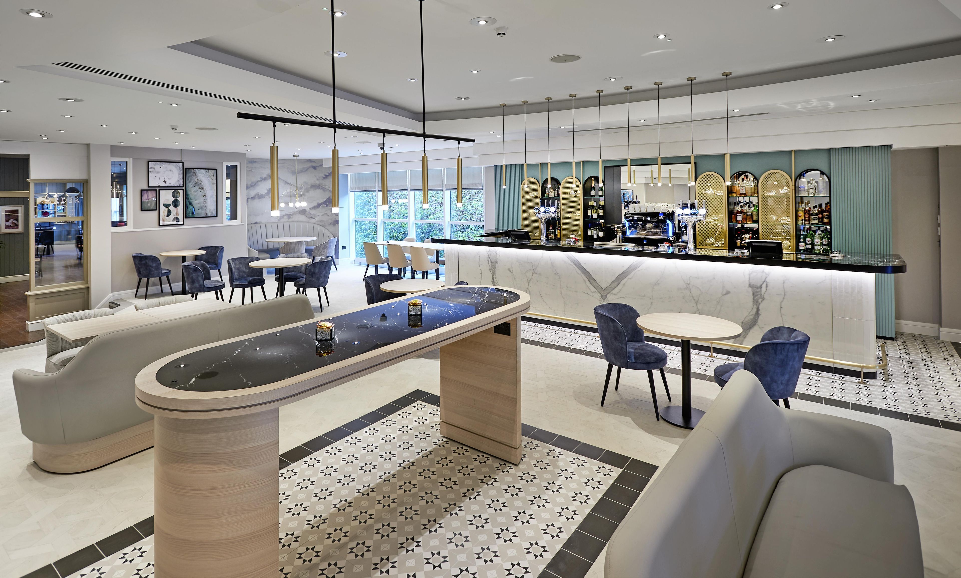 A modern bar area with marble countertops, seating, and a patterned floor.