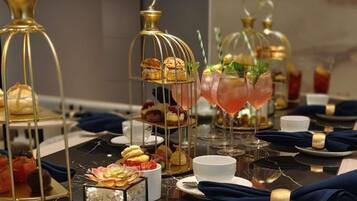 A table set with various desserts in glass containers, a pink cocktail, and a gold-colored birdcage.
