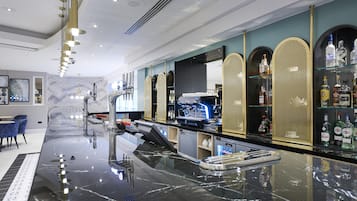 A modern bar area with a marble countertop, espresso machines, and a selection of liquor bottles.