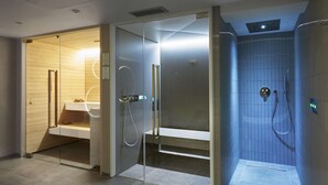 A modern bathroom with a glass shower enclosure, a wooden vanity, and a built-in bench.