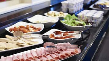 Un bufé con diversos alimentos, incluyendo carnes cortadas, ensaladas y productos lácteos.
