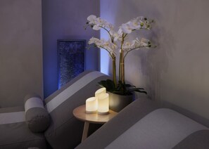 A modern lounge area with a sofa, a small table with candles, and a potted orchid plant. - Hilton London Croydon (Croydon)