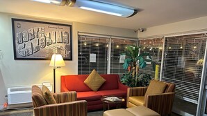 A lobby with a red sofa, striped armchairs, a small table, and a large plant.