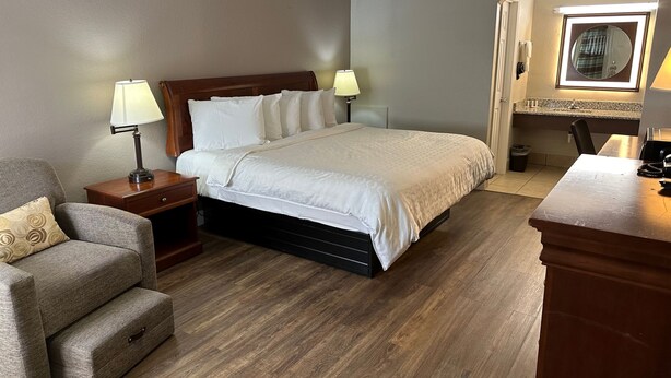 A hotel room with a bed, a nightstand, a chair, a desk, and a mirror.