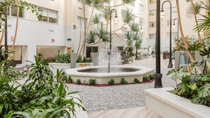 A courtyard with a central fountain, surrounded by palm trees and potted plants. - Brent House Hotel (New Orleans)