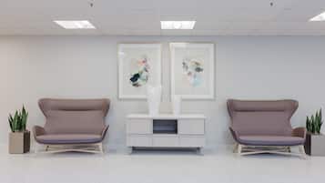 A reception area with two chairs, a console table, and two abstract paintings on the wall.
