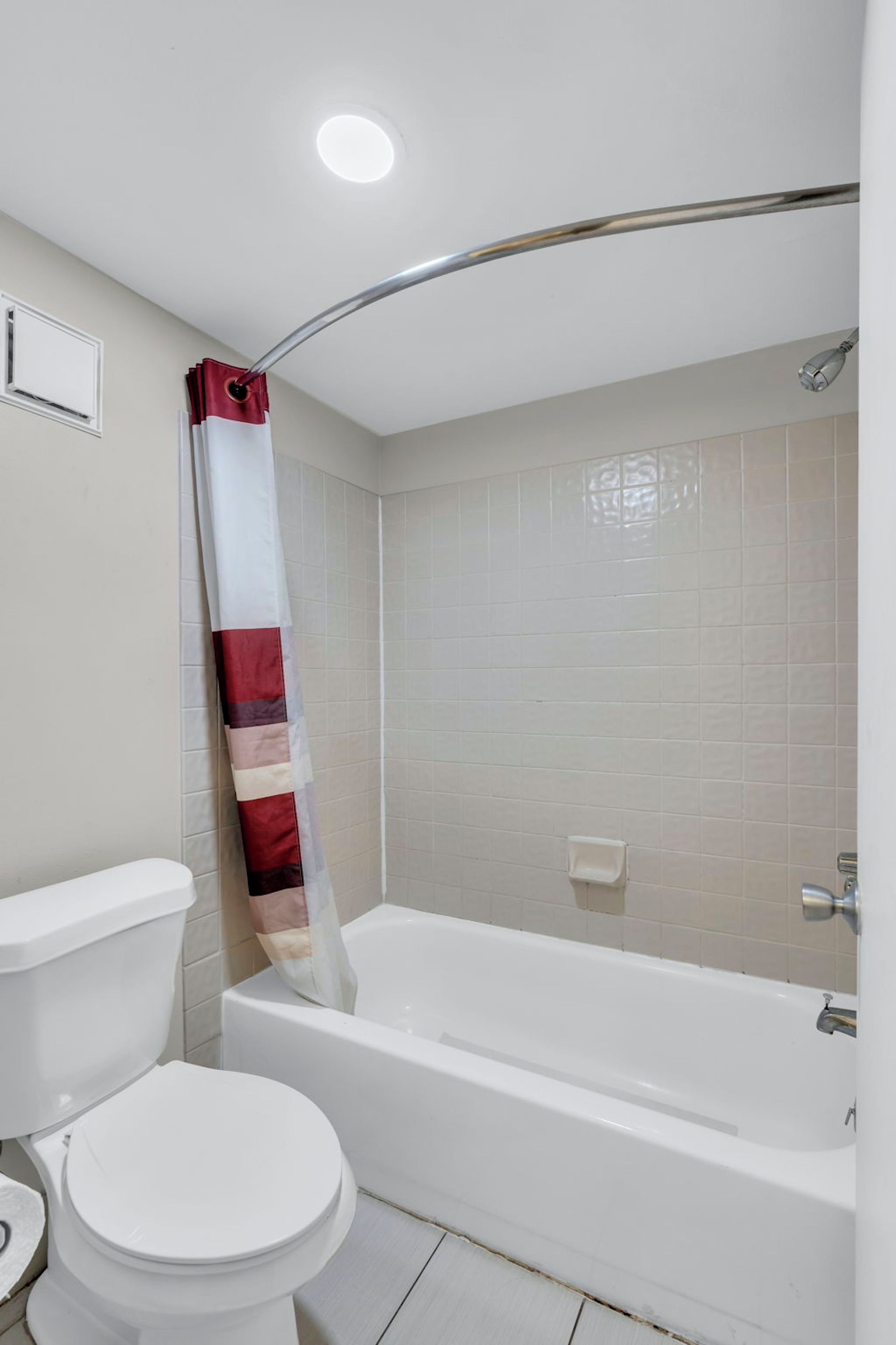 A bathroom with a toilet, a bathtub, and a shower curtain.
