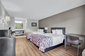A hotel room with a large bed, a desk, a chair, a kitchenette, and a window with a view of greenery. - Red Roof Inn MacClenny (MacClenny)