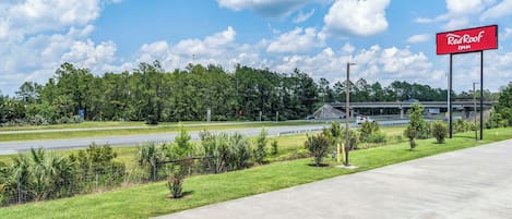 Señal de Red Roof Inn, una autopista y un área verde con árboles.