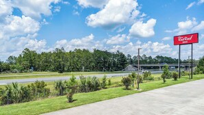 A Red Roof Inn sign, a highway, and a grassy area with trees. - Red Roof Inn MacClenny (MacClenny)