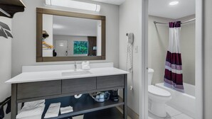 A bathroom with a white sink, mirror, and a shower curtain. - Red Roof Inn MacClenny (MacClenny)