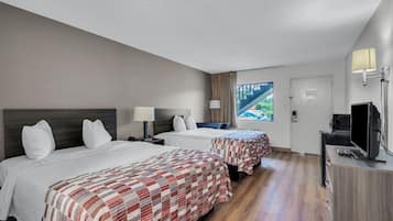 Quarto de hotel com duas camas, uma televisão e uma janela com vista para uma ponte.