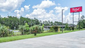 A Red Roof Inn sign, a parking lot, and a highway overpass. - Red Roof Inn MacClenny (MacClenny)