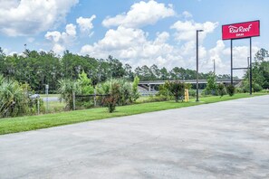 A Red Roof Inn sign, a parking lot, and a highway overpass. - Red Roof Inn MacClenny (MacClenny)