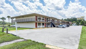 A motel with a two-story structure, a parking lot, and a clear sky with clouds. - Red Roof Inn MacClenny (MacClenny)