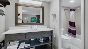 A bathroom with a white sink, mirror, and a shower curtain. - Red Roof Inn MacClenny (MacClenny)