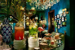 Uma área de bar com um grande dispensador de bebidas, uma decoração de flamingo e diversos displays de comida e bebida.