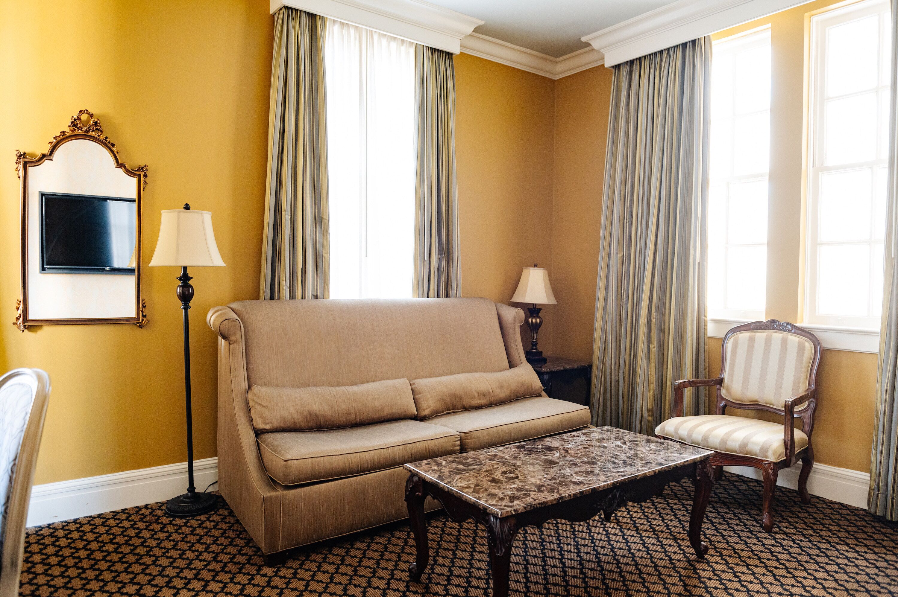 A room with a sofa, a chair, a table, and a floor lamp.