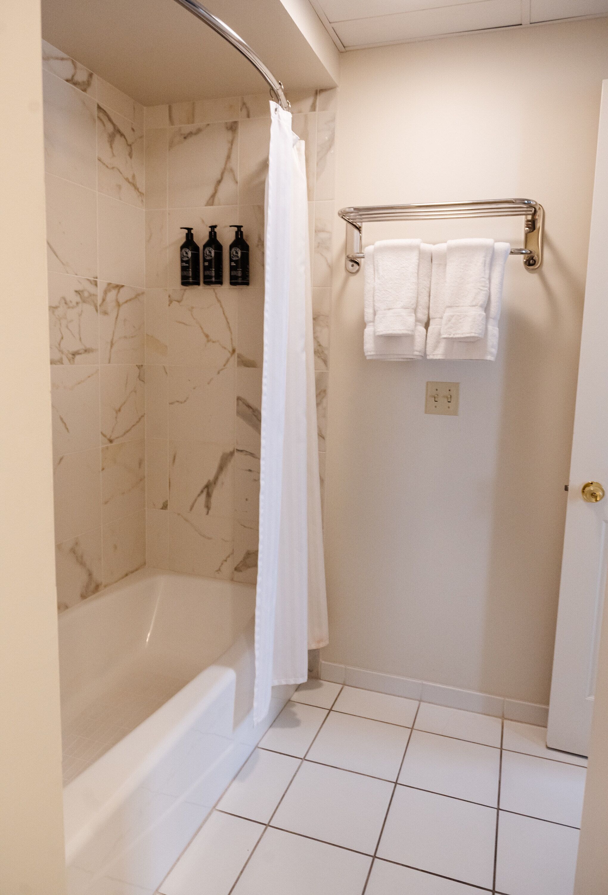 Une salle de bain avec une douche en marbre, une baignoire et un porte-serviettes avec deux serviettes.