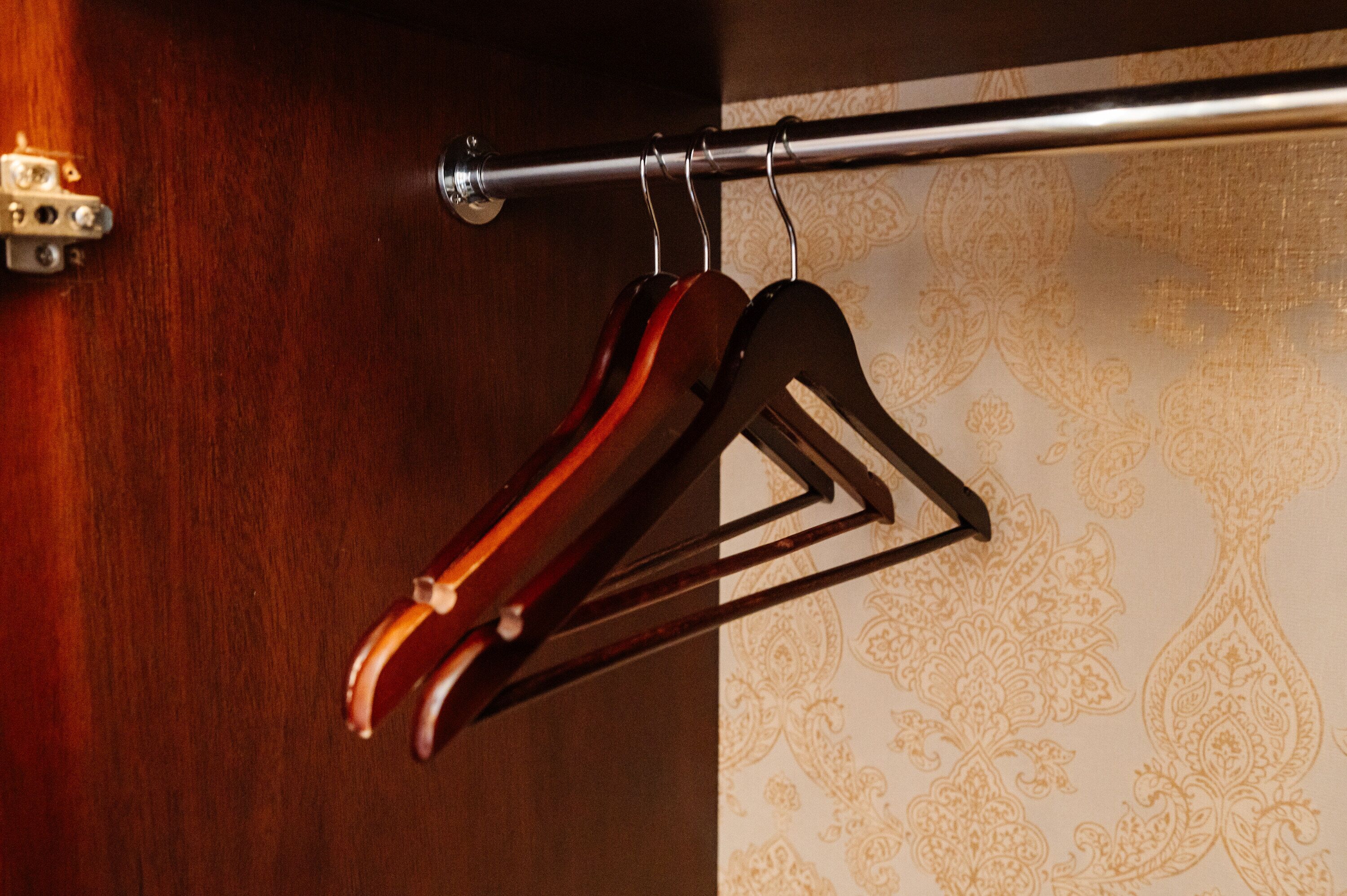 Un perchero de madera con una barra metálica fijada a la pared, probablemente en una habitación de hotel.