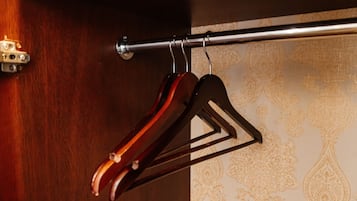Un perchero de madera con una barra metálica fijada a la pared, probablemente en una habitación de hotel.