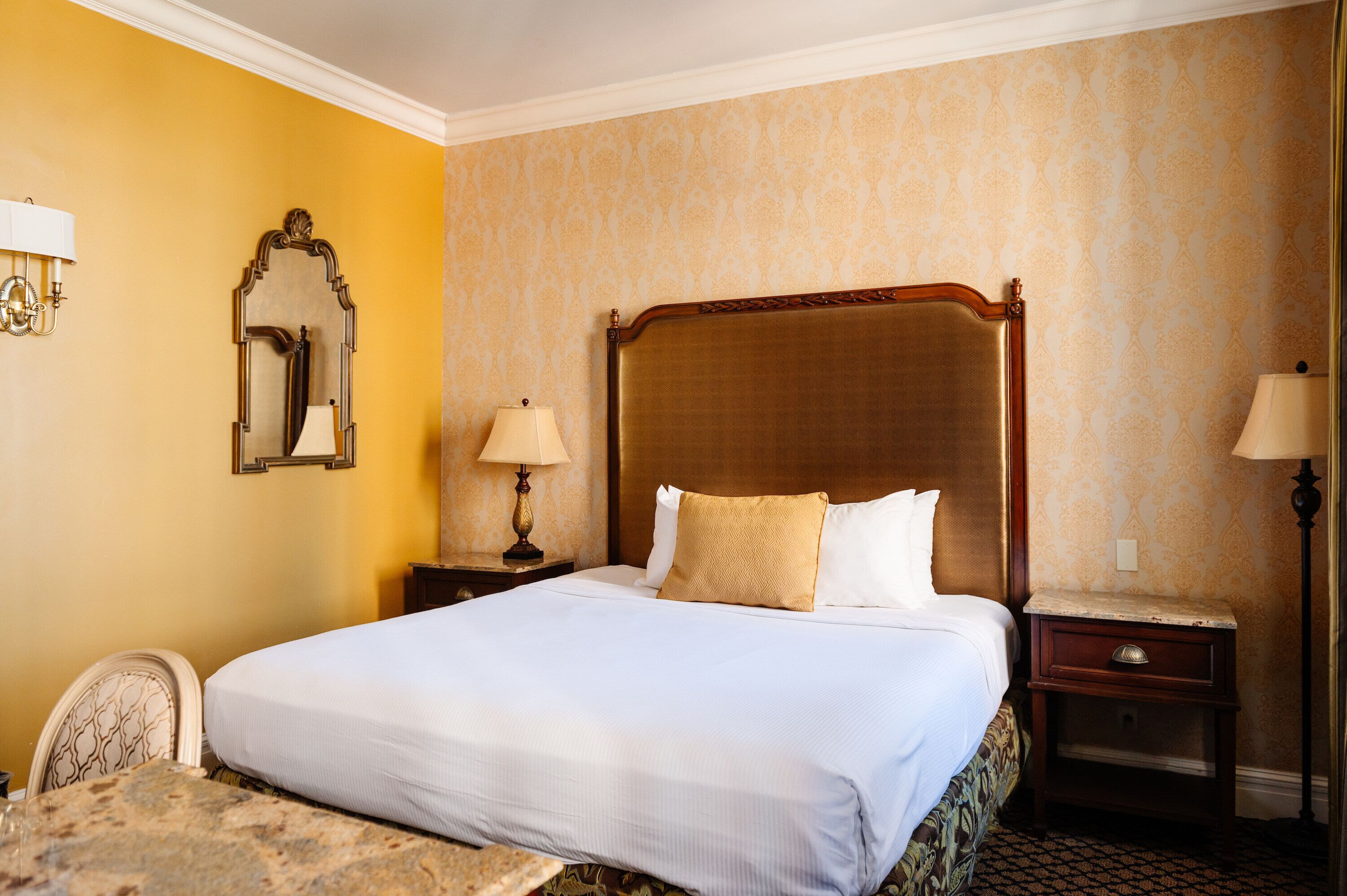 A hotel room with a large bed, two bedside tables with lamps, a chair, and a small table.