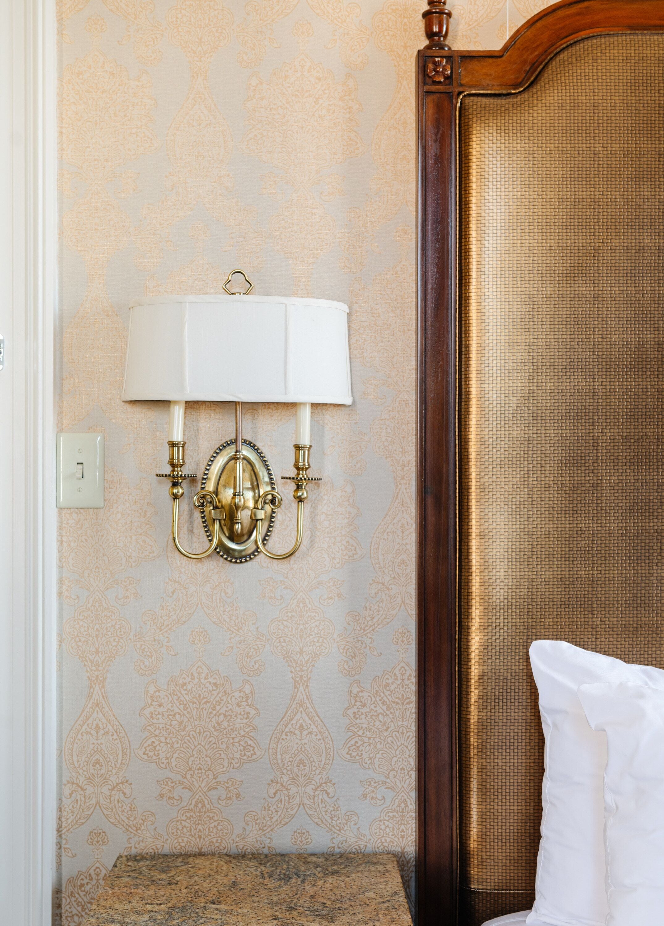 Ein Zimmer mit einem Bett, einer Wandlampe und einer Wand mit Struktur.