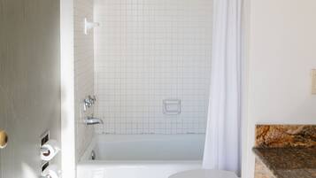 Un baño con bañera, inodoro y cortina de ducha.