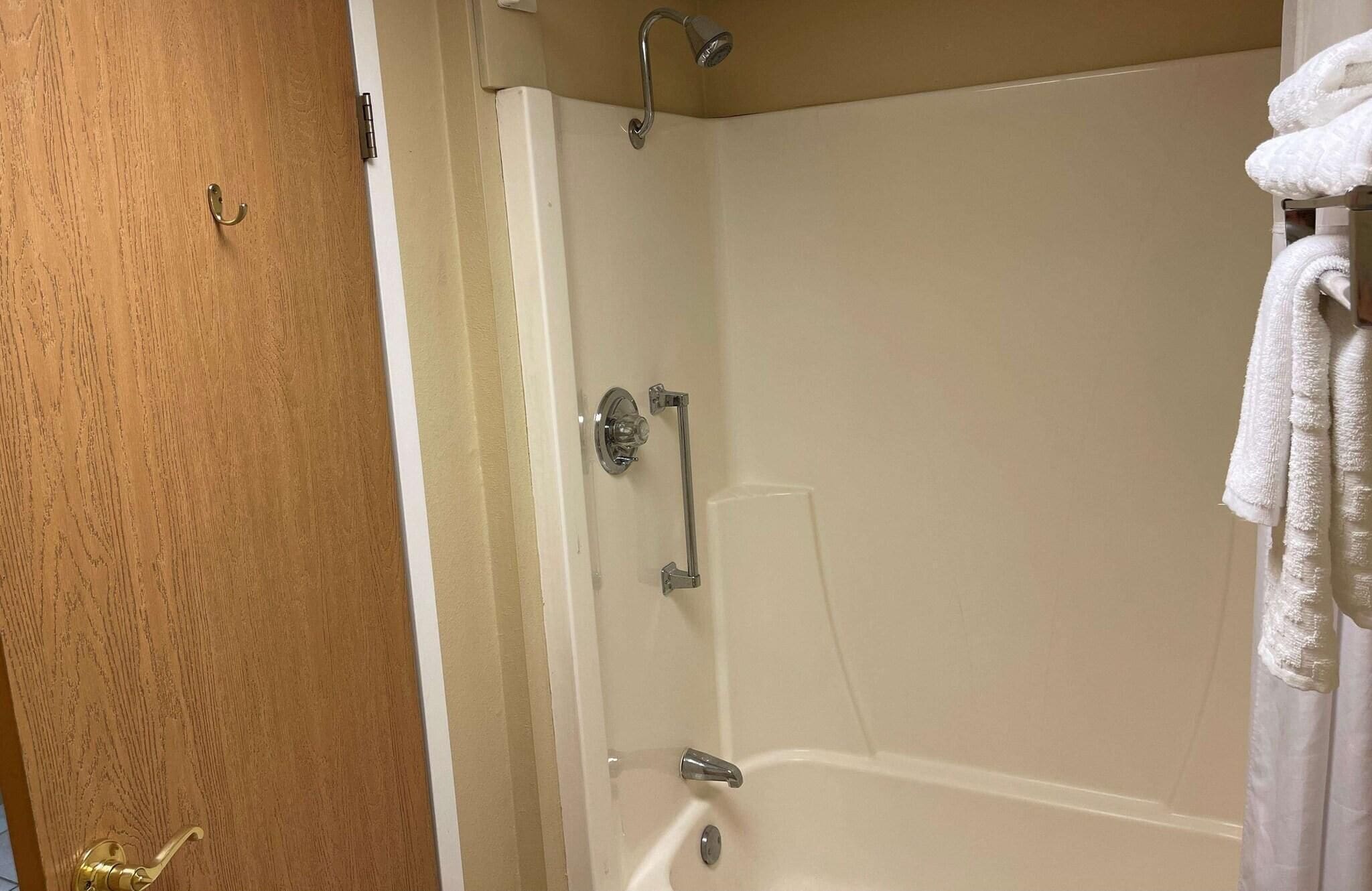 Un baño con bañera, ducha y barra para toallas.
