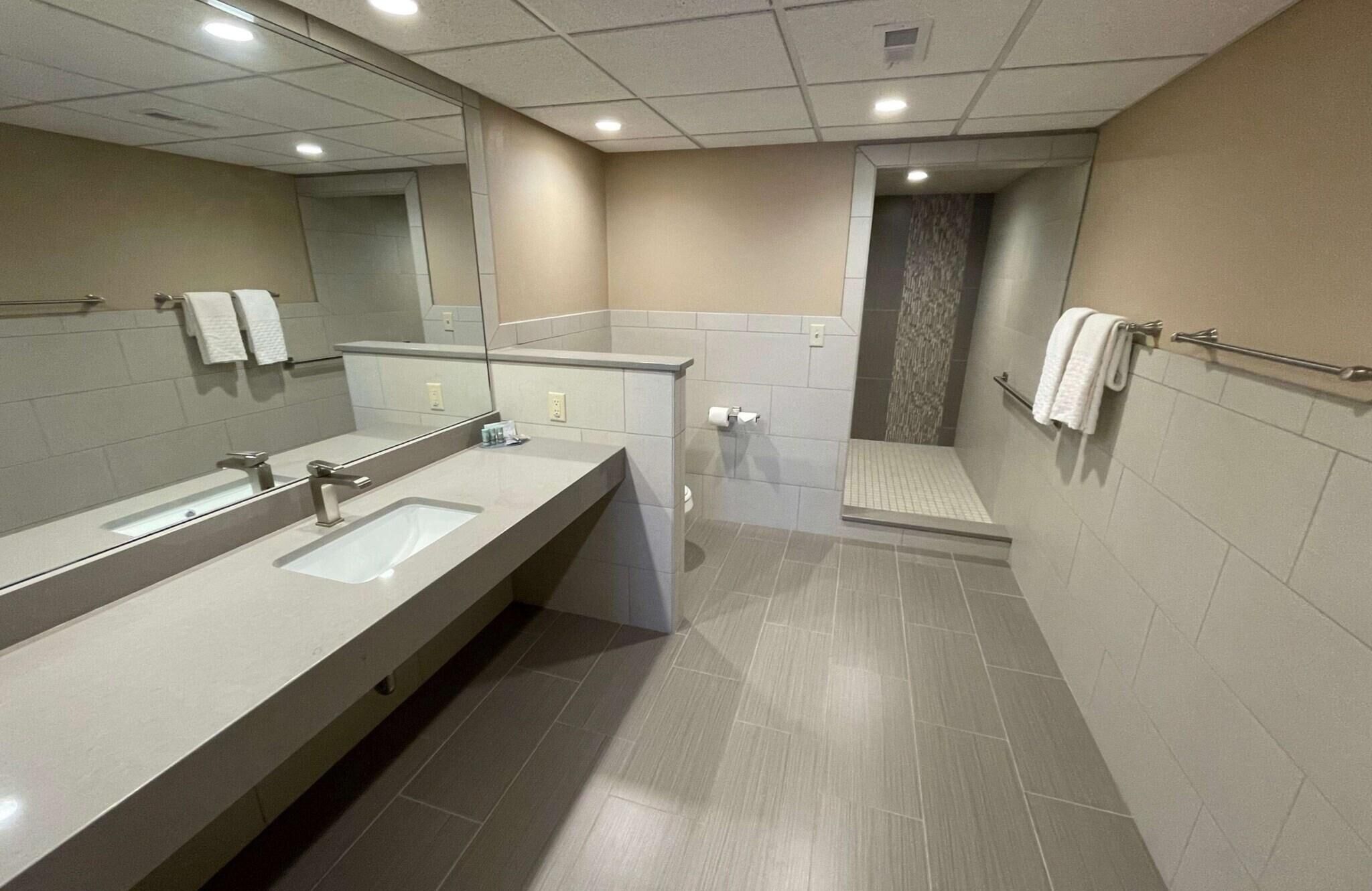 Un baño moderno con un mueble lavamanos amplio, una zona de ducha y un inodoro.