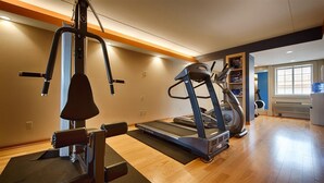 A gym with a treadmill, elliptical, and weight machine. - Crossroads Hotel and Event Center (Fort Dodge)
