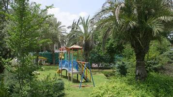Children can play on the climbing frame and swing set in a spacious garden surrounded by lush greenery.