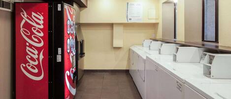A hotel restroom with a Coca-Cola vending machine, a mirror, and a row of sinks.