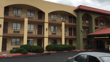 A multi-story hotel with balconies, a parking area, and a 'No Parking' sign.